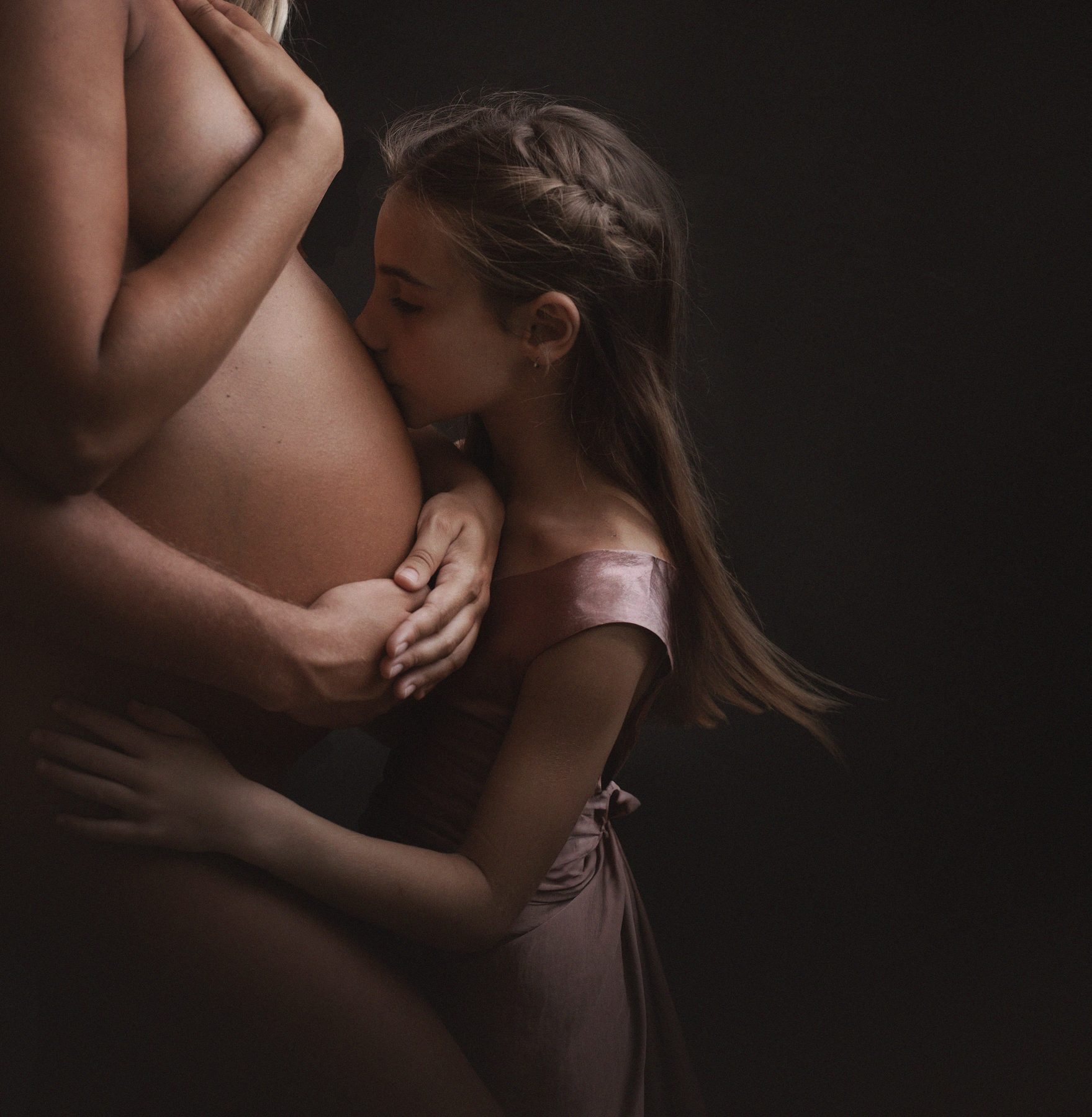 Hija mayor besando la barriga de su madre embarazada