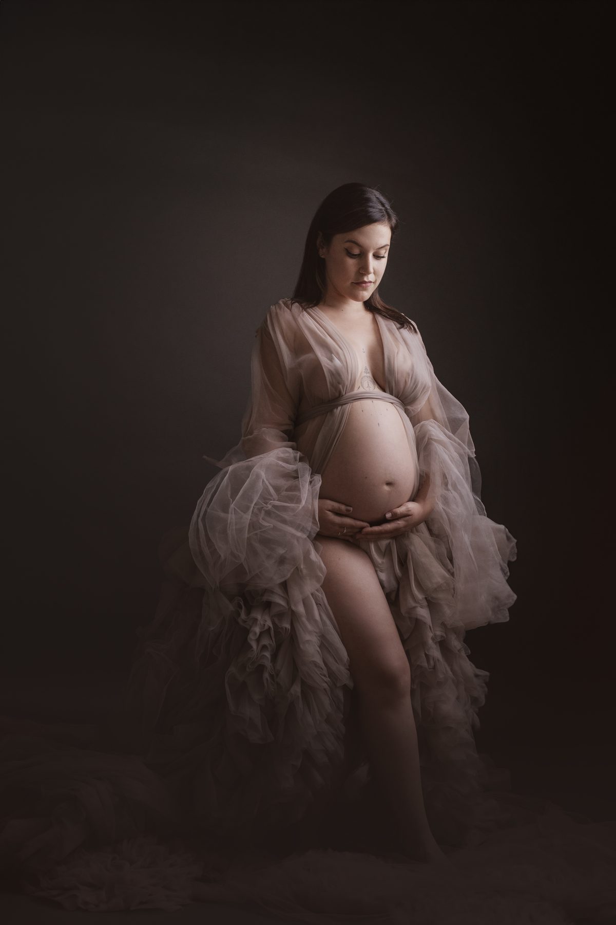 Embarazada con bata de tul en el estudio, ejemplo de vestuario para una sesión de fotos de embarazo