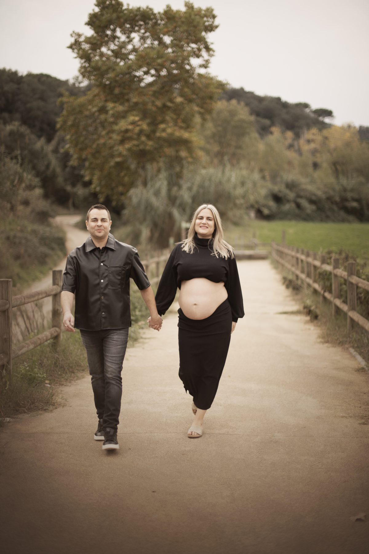 Pareja caminando por el bosque durante una sesión de embarazo en Sant Celoni