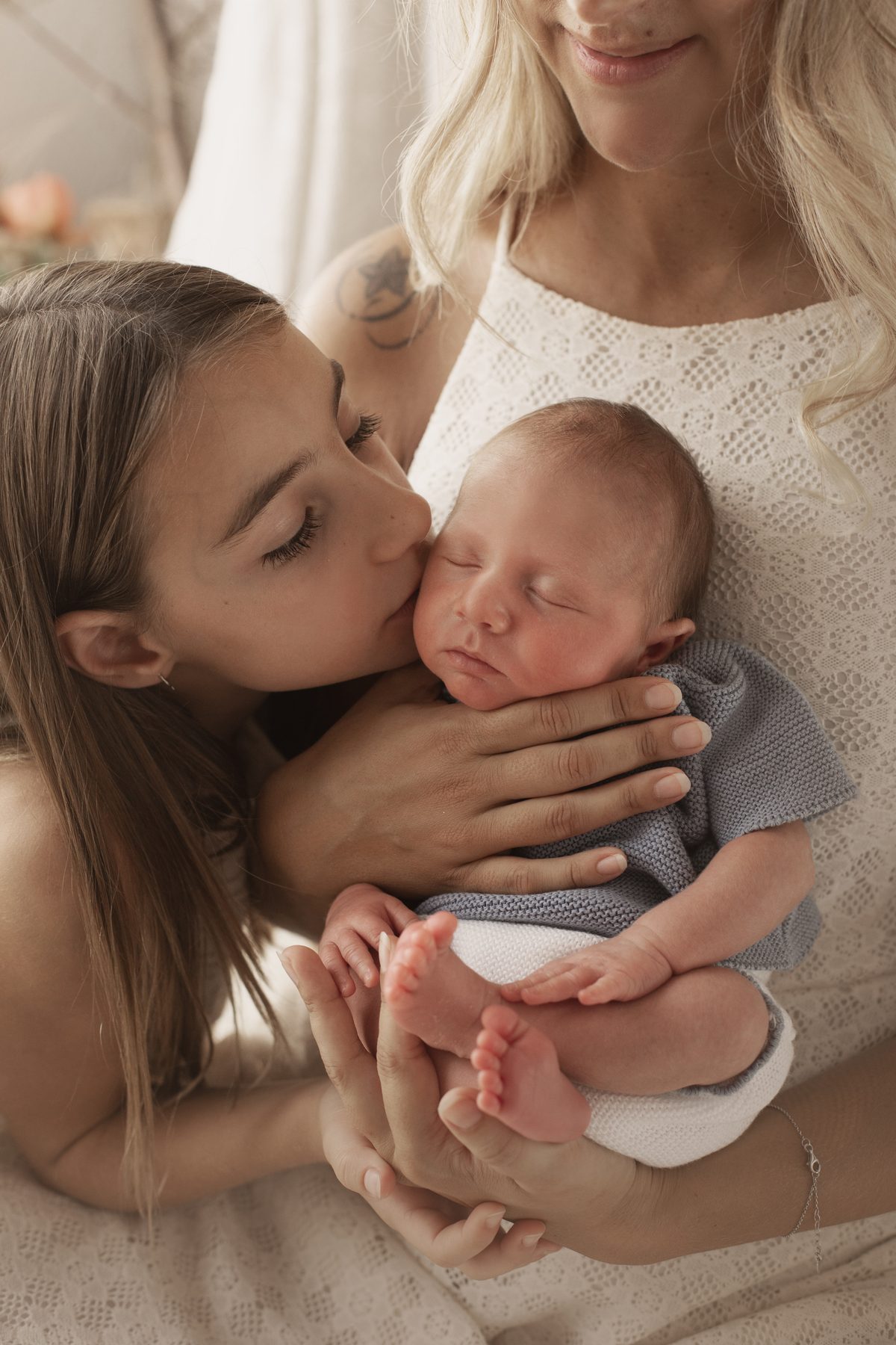 Hermana mayor besando al recién nacido en una sesión newborn