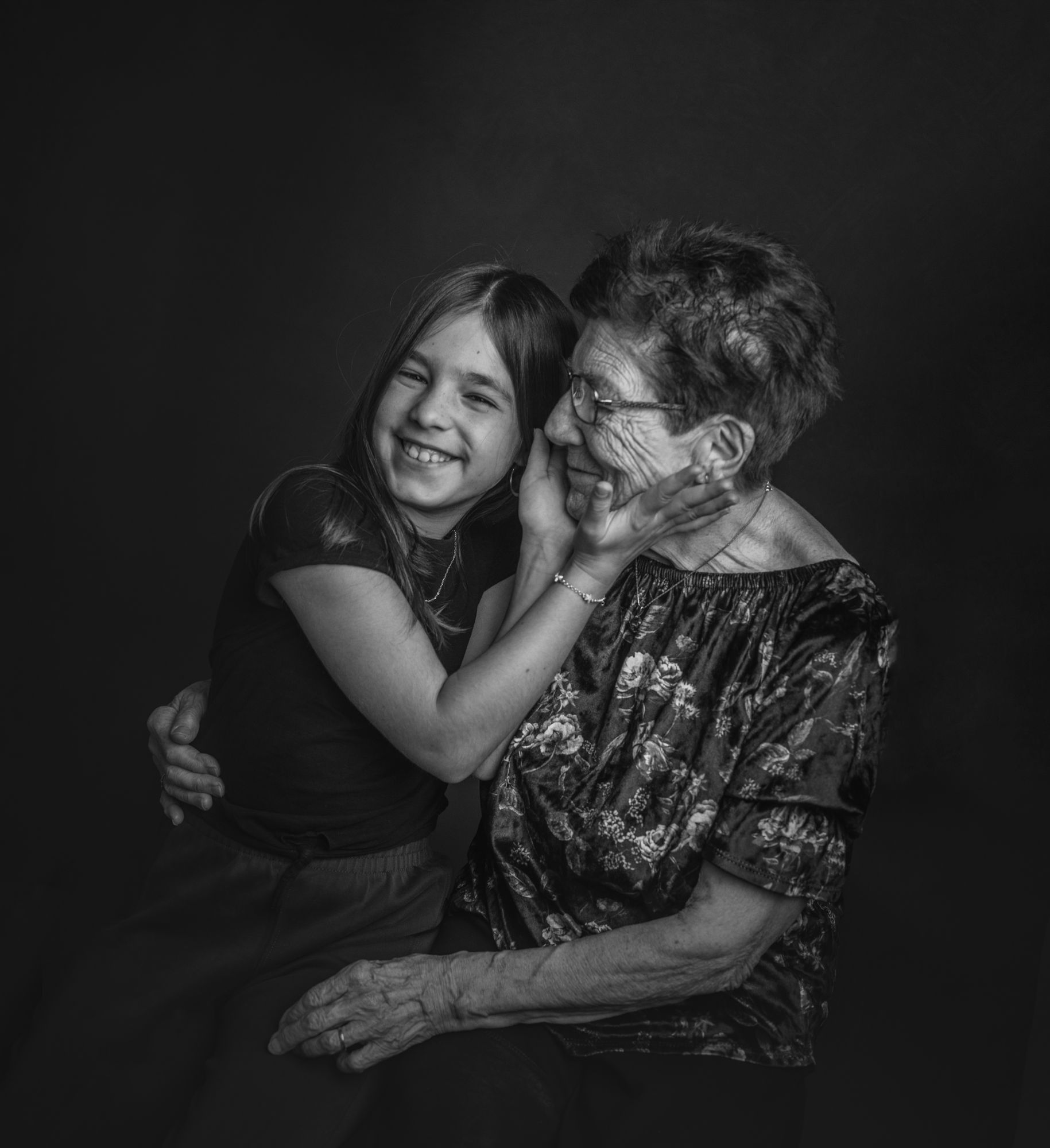 Abuela y nieta riendo mejilla con mejilla, en blanco y negro