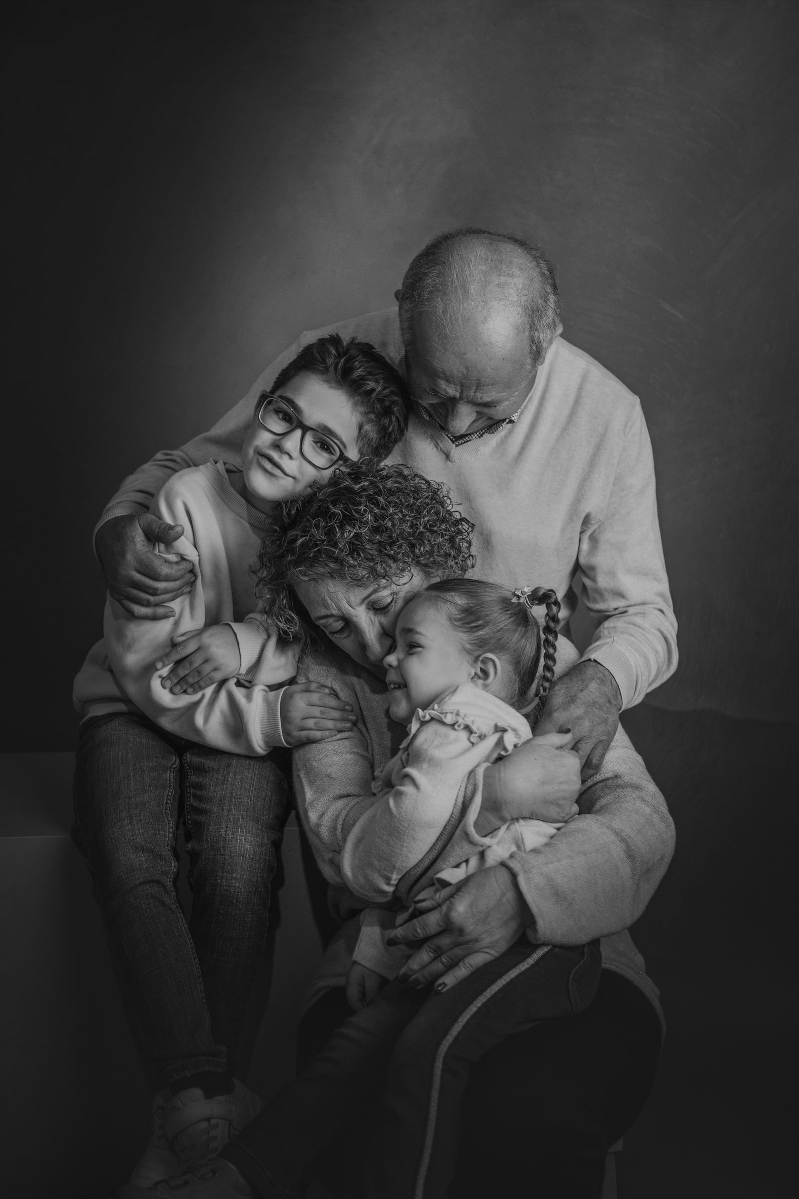 Abuelo abrazando a sus tres nietos en el estudio, blanco y negro