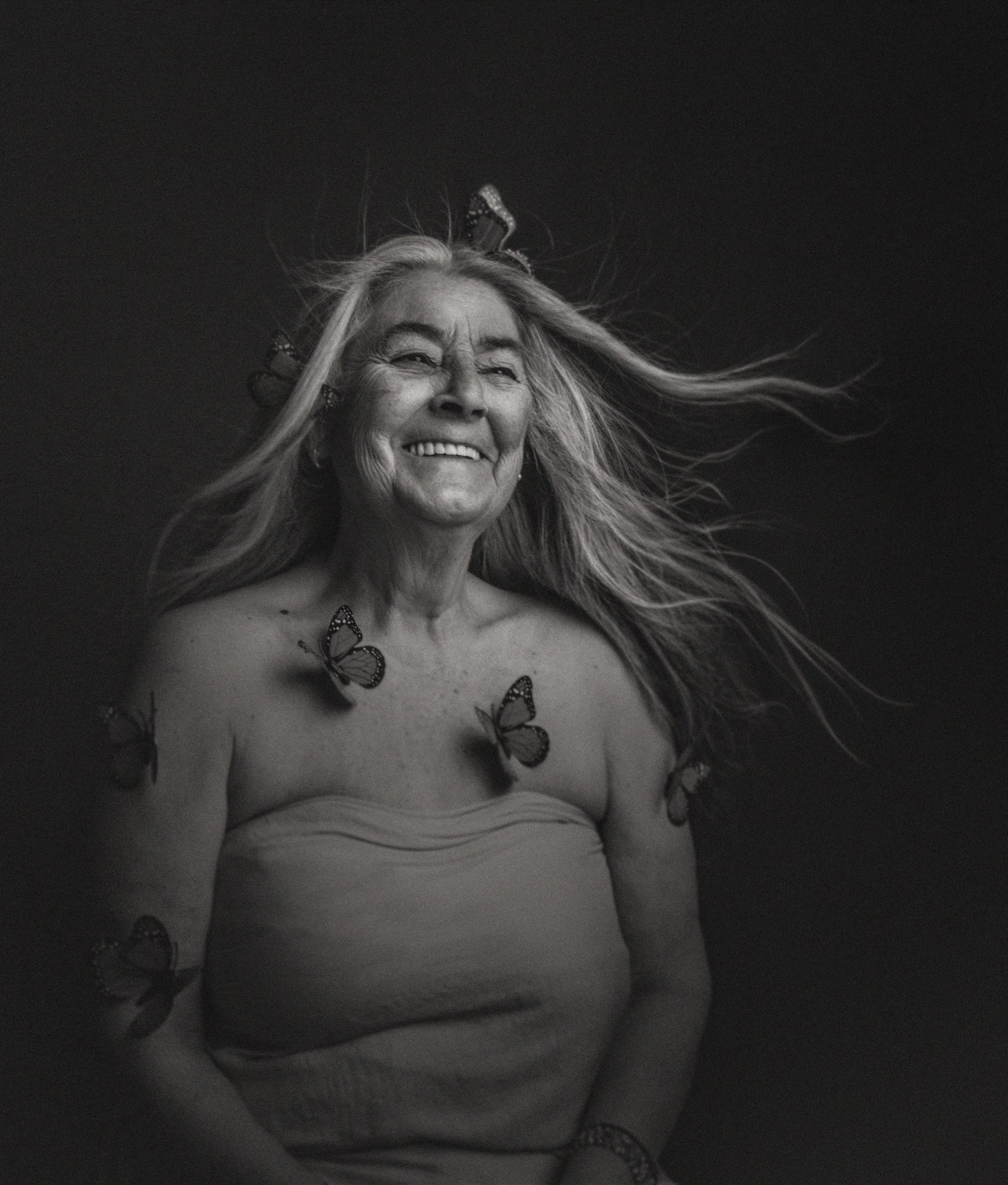 Mujer mayor con el pelo al viento y mariposas