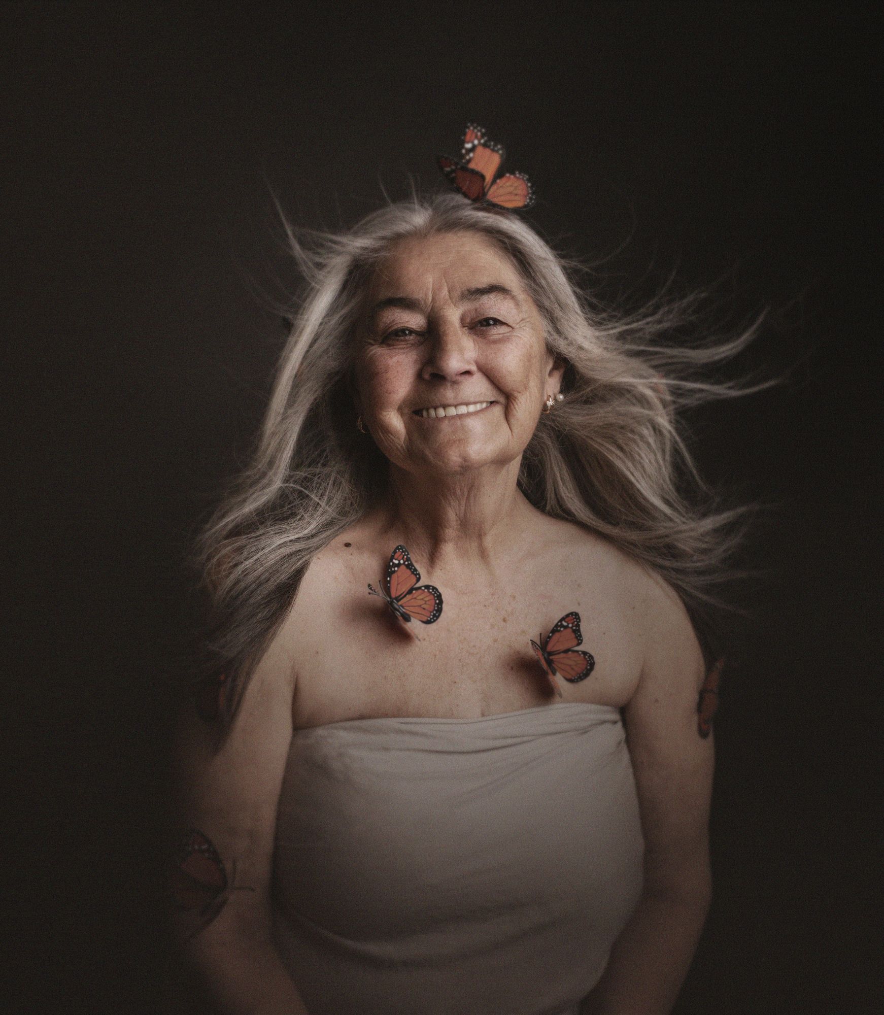 Mujer mayor sonriendo con mariposas sobre la piel