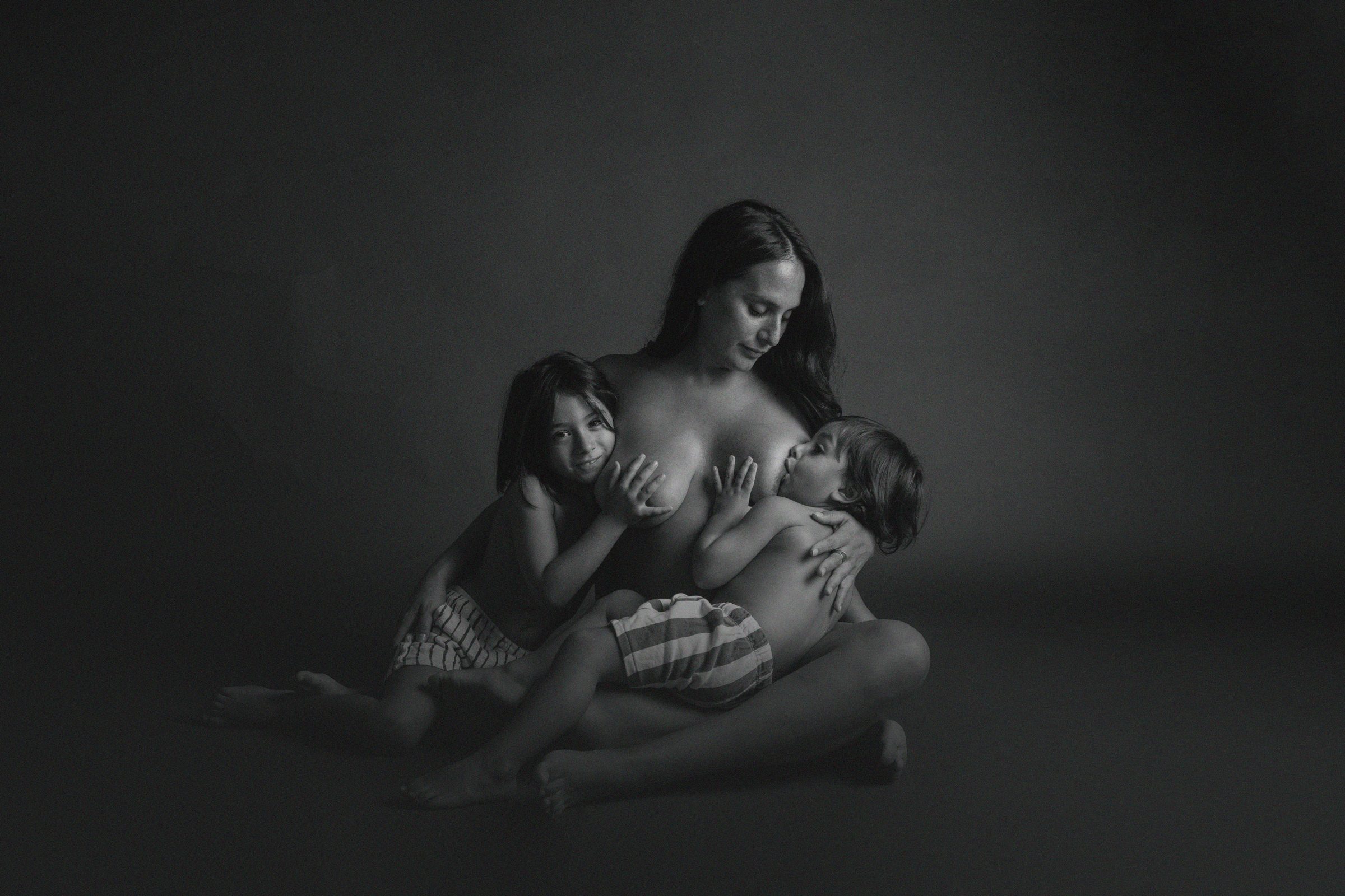 Madre amamantando a sus dos hijos en el estudio, blanco y negro